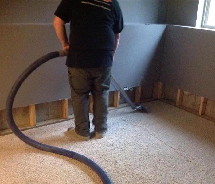 A SERVPRO technician using hose to extract water from carpeting