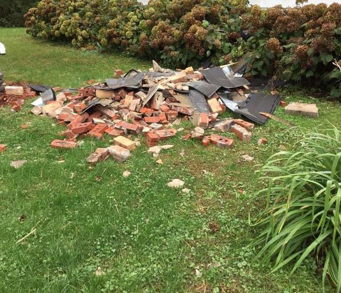 A pile of bricks lay haphazardly on the front lawn of residence.