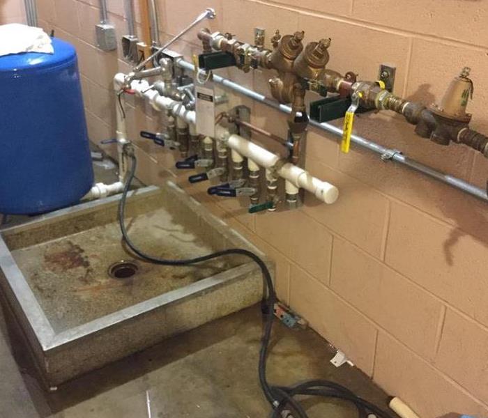 A long row of pipes and spigots with connective tubing over a drain  